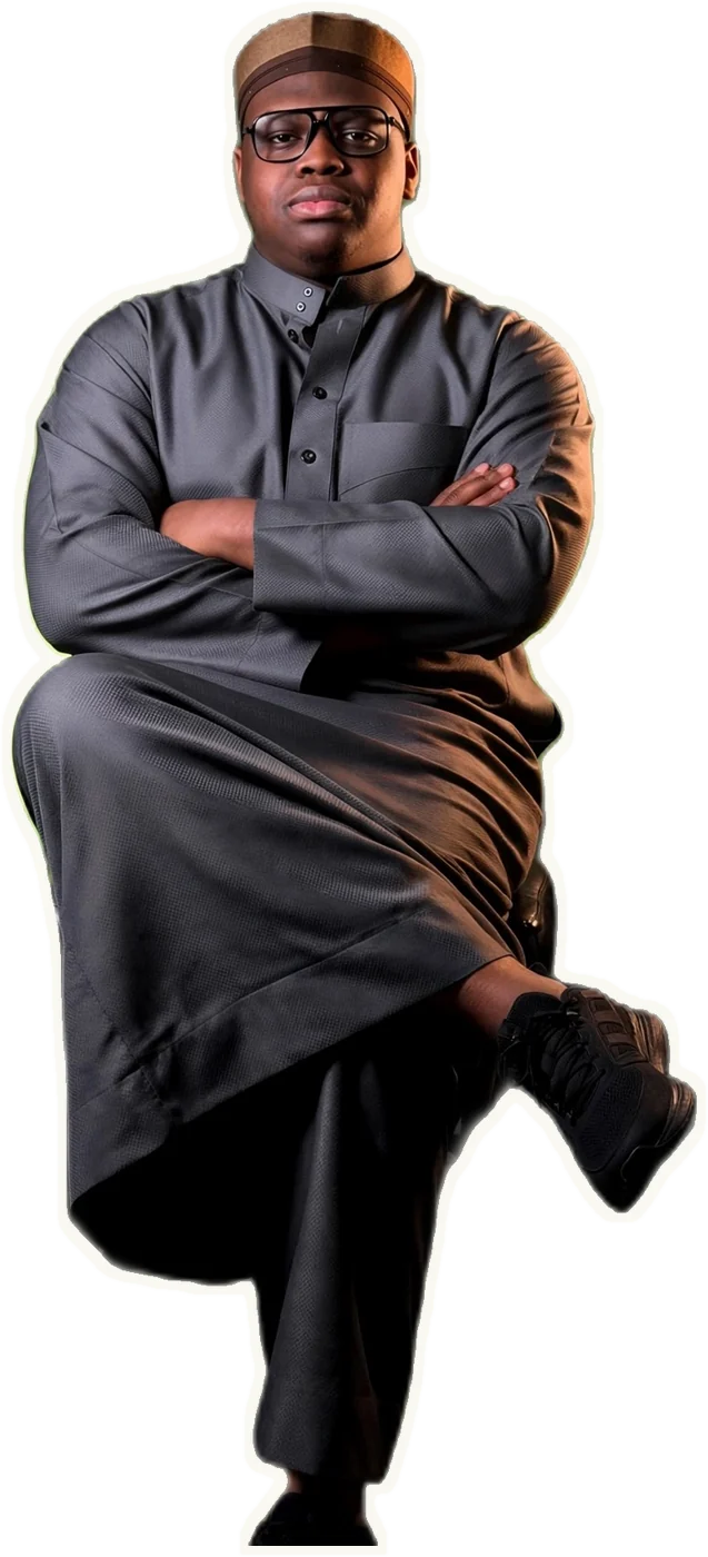 Abdul seated, arms crossed, in a grey thobe.